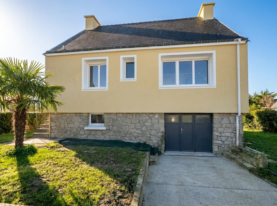 Maison individuelle à deux niveaux, façade enduit jaune ocre sur soubassement en pierre de granit appareillé