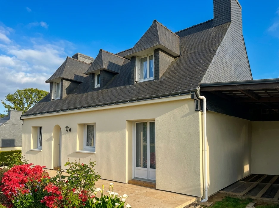 Maison individuelle de style breton, façade enduite crème, toiture en ardoise naturelle avec lucarnes à capucine