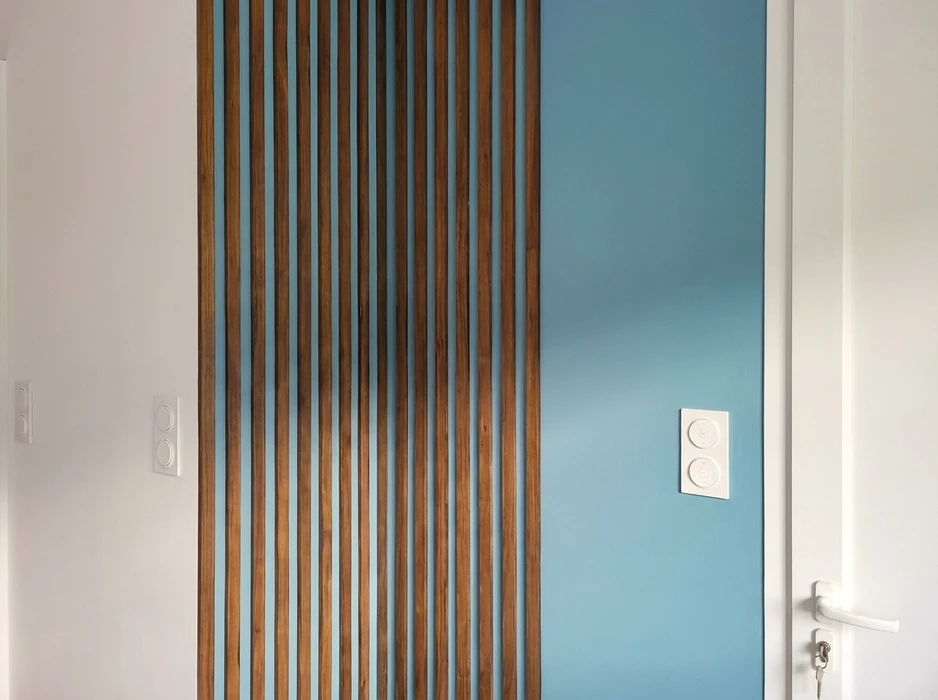 Couloir d'appartement moderne avec claustra en tasseaux de bois massif teinte noyer, fixés verticalement sur toute la hauteur
