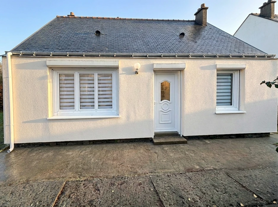 Façade d'une maison de plain-pied de style breton, enduit blanc, toiture en ardoise naturelle