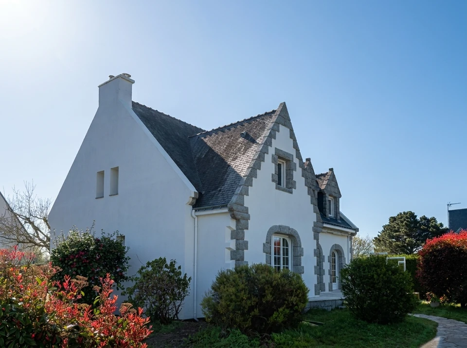 Maison individuelle en enduit blanc, toiture en ardoise naturelle avec coyau décoratif festonné