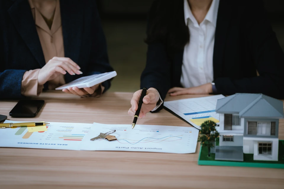 Homme d'affaires en chemise bleue travaillant sur ordinateur portable avec documents et graphiques financiers sur bureau
